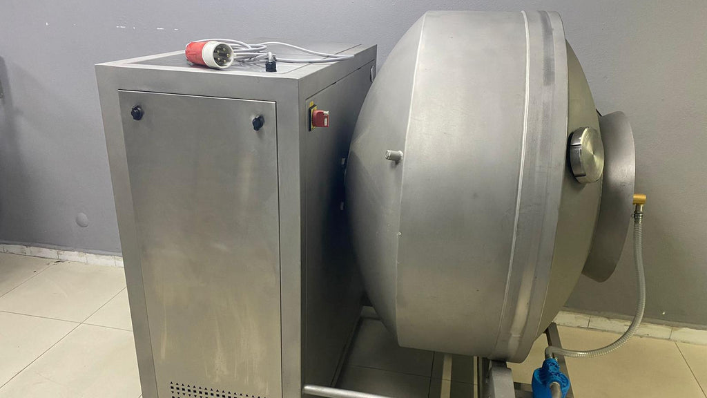 Stainless steel industrial machine with a cylindrical component on a tiled floor against a gray wall.